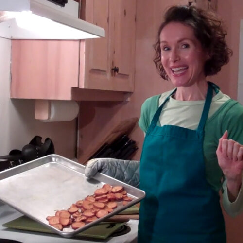 Health Coach, Mo the Morselist, in the kitchen holding a tray of baked sweet potato chips.